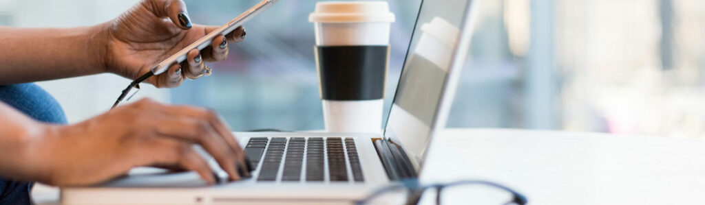 Laptop, Smartphone und ein Kaffeebecher auf dem Schreibtisch